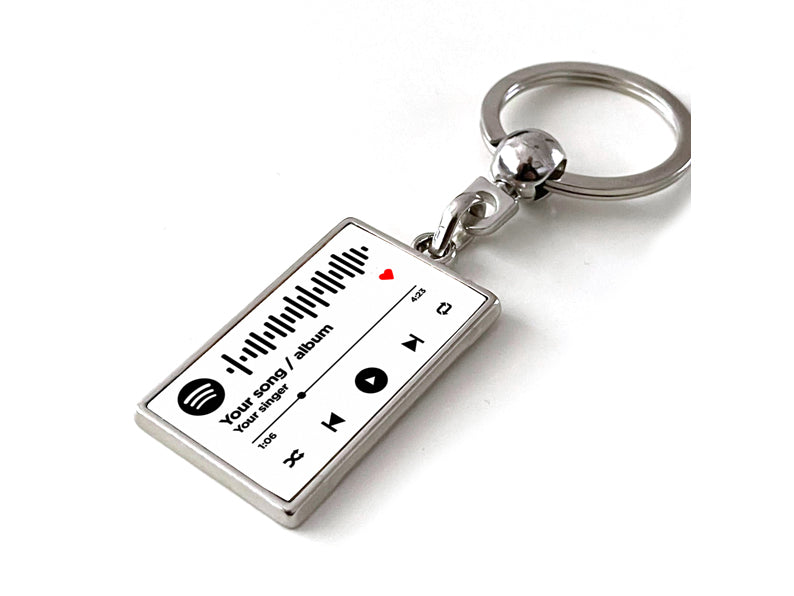 Gepersonaliseerde witte Spotify code sleutelhanger met afspeelknoppen en albuminformatie. Uniek cadeau voor muziekliefhebbers of als stijlvol accessoire.